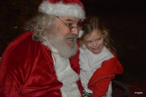 Santa poses with a child for a photo opportunity after listening to her wish list this evening.