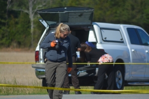 An SBI agent examines a portion of Macon Price Road near where the woman&#039;s body was located.